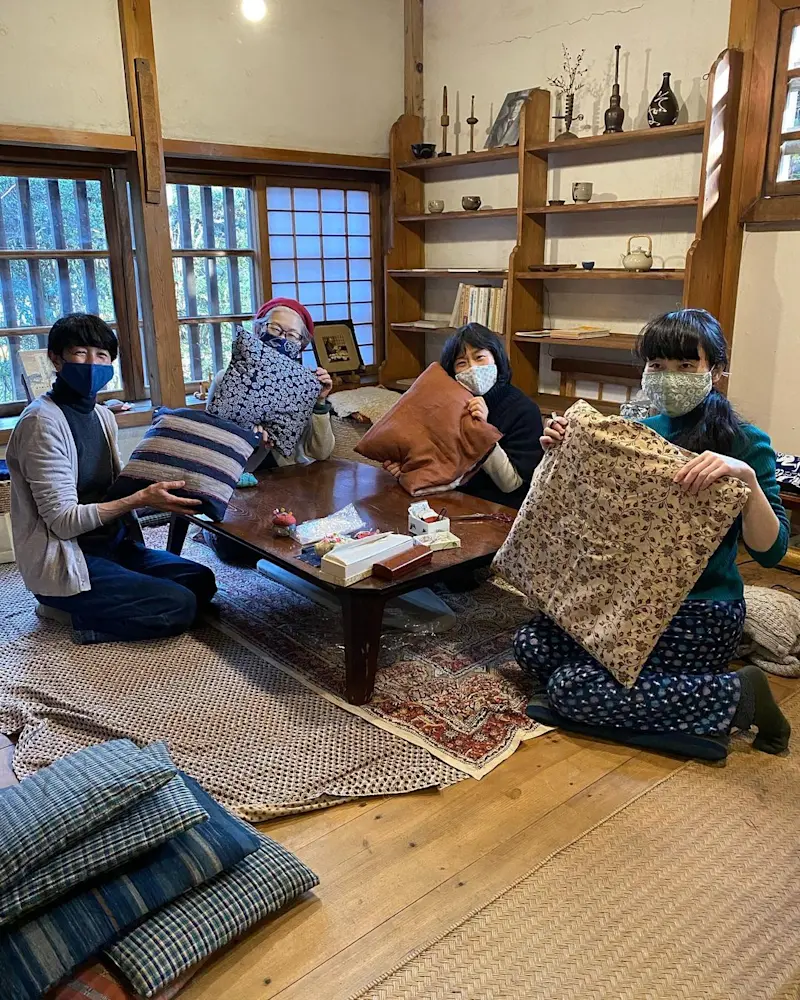 Four people showing off their zabuton after indulging into the Japanese traditional pillow-making art class in Tokyo.