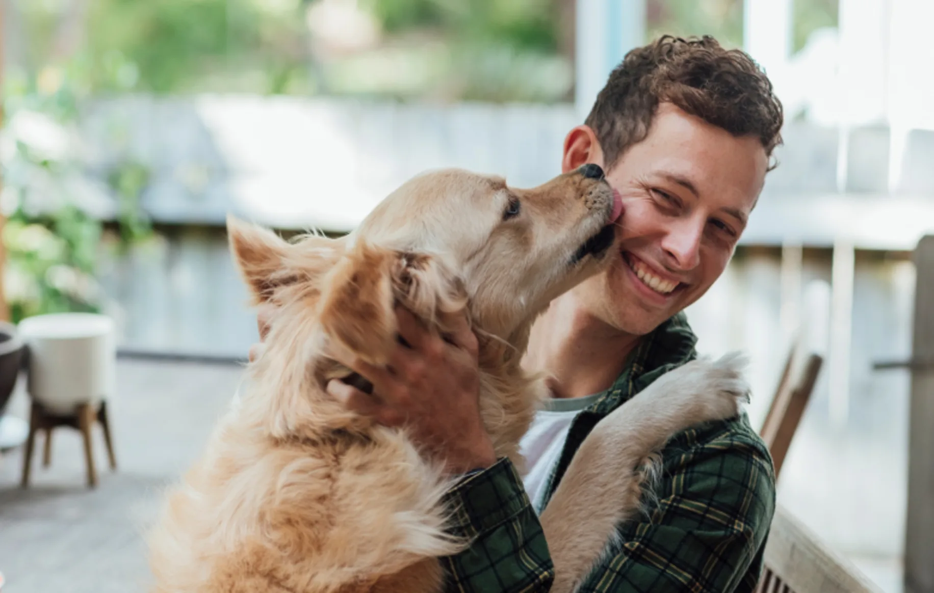 Happy pet owner smiling while holding a golden retriever dog