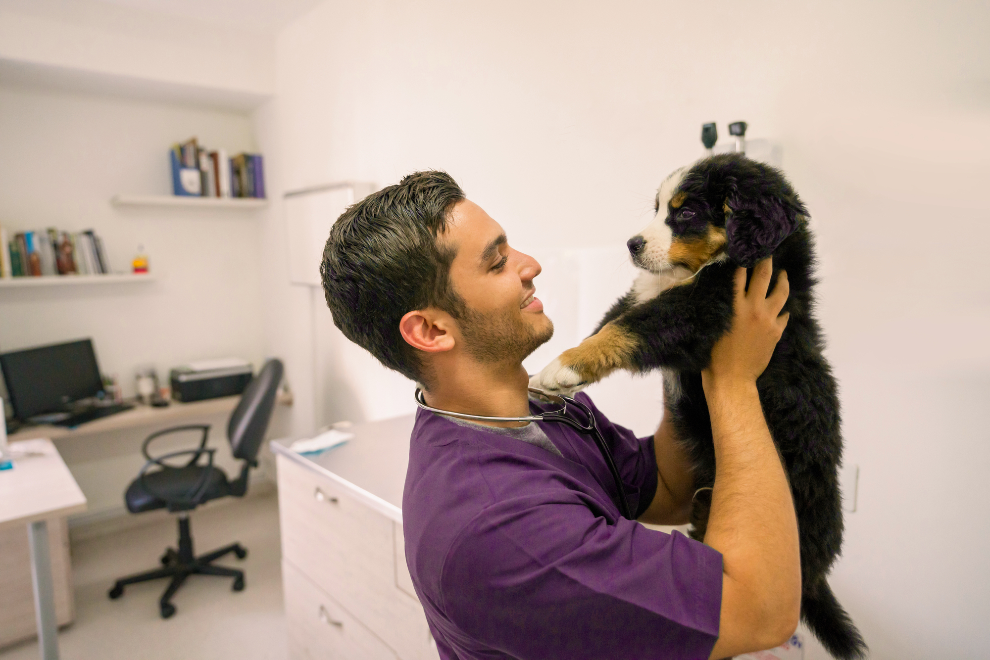 man in purple scrubs holding a puppy