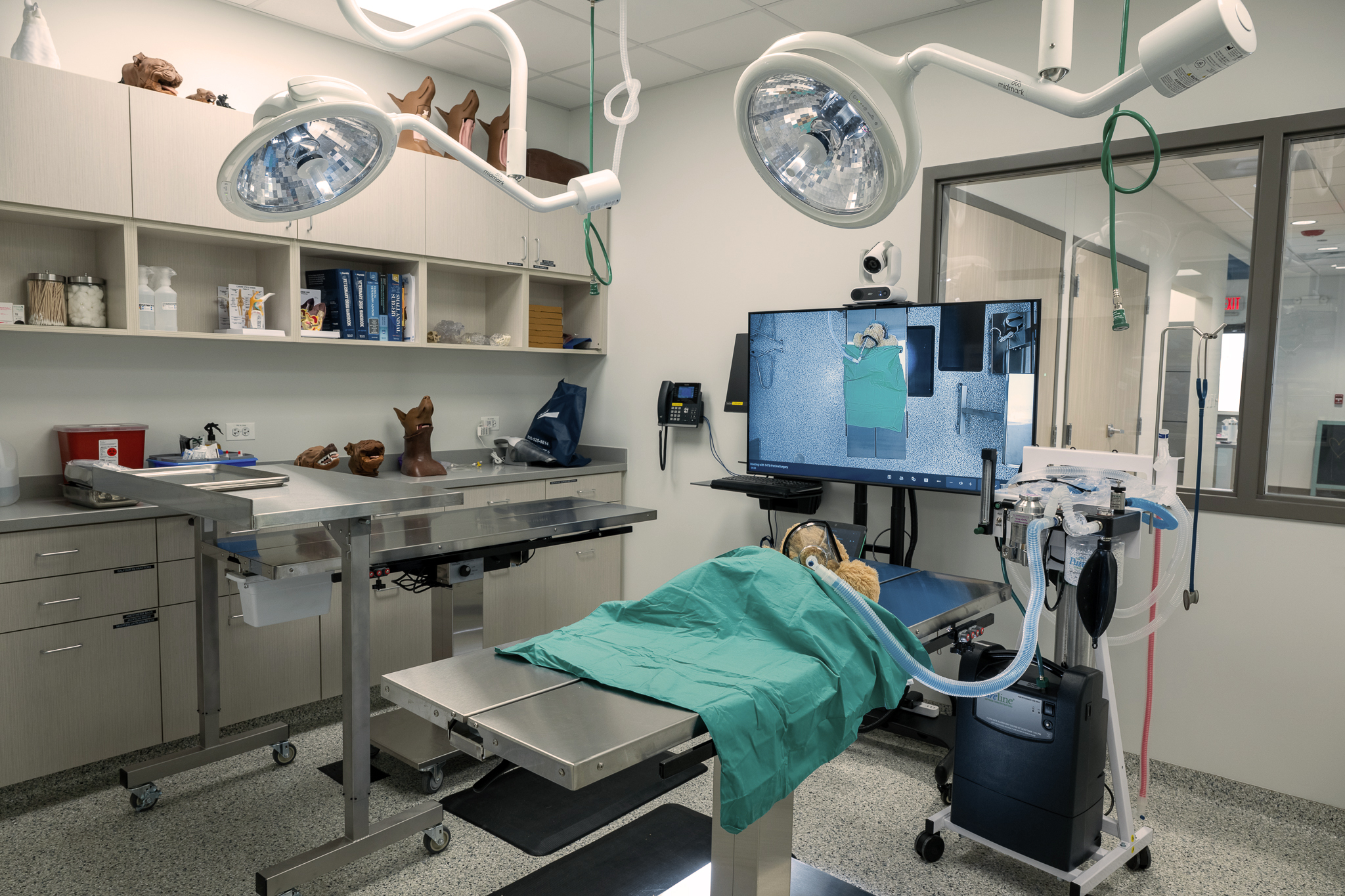 A dog lying down covered on a modern surgery table with many screens and technology around them