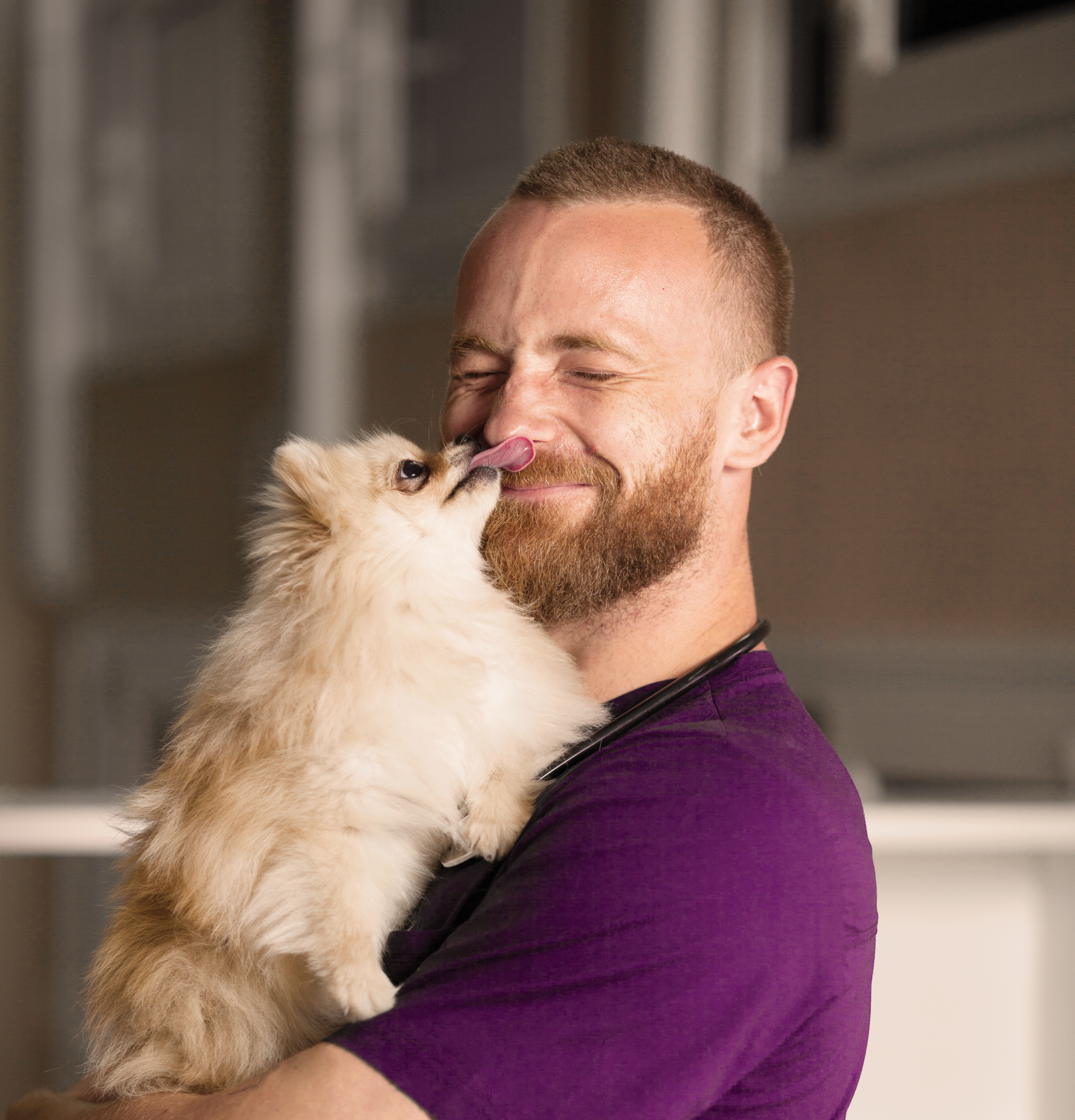 man in purple holding dog
