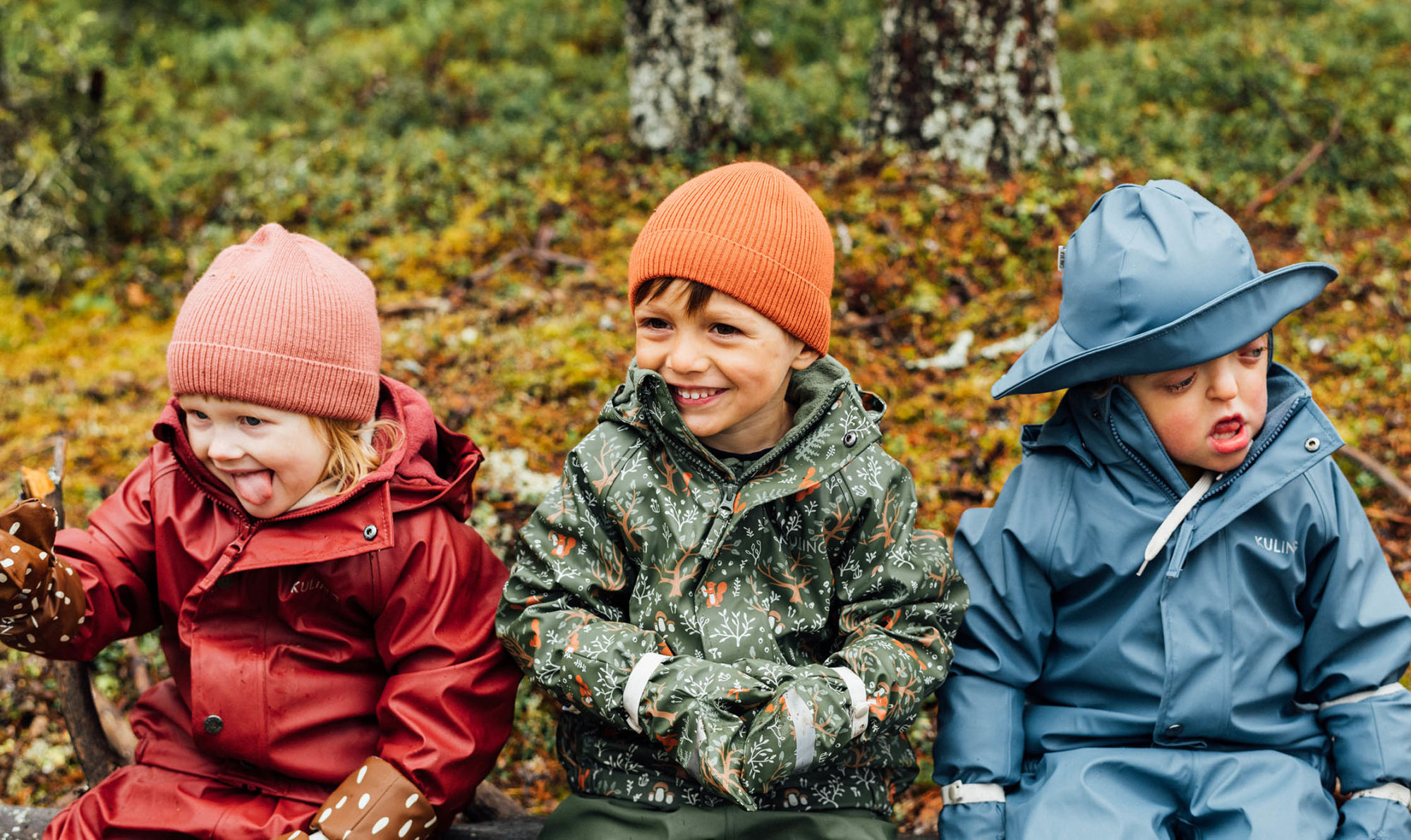 Kids sitting in a forest on a log wearing fall clothes from Kuling - Babyshop