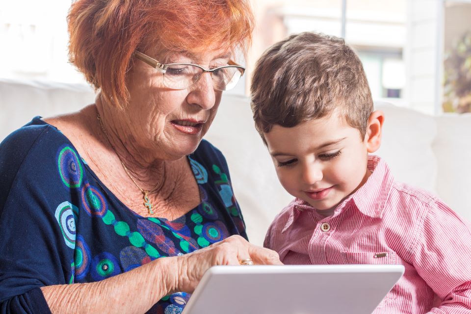 Grandmother with grandson playing on the tablet at home.