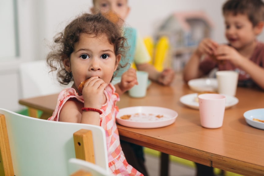A young child eats lunch in a nursery environment