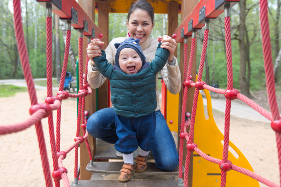 A practitioner and child playing outside on a playground 