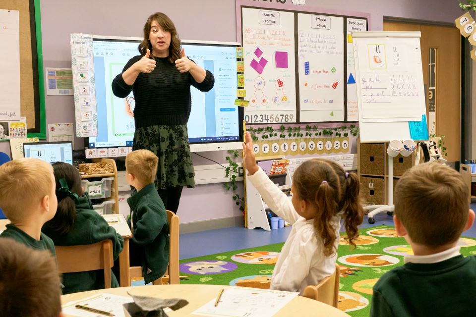 images/Teacher giving thumbs up to children in classroom