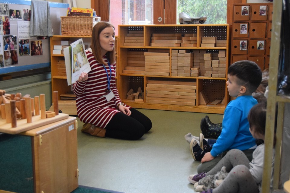 Practitioner reading to a group of children