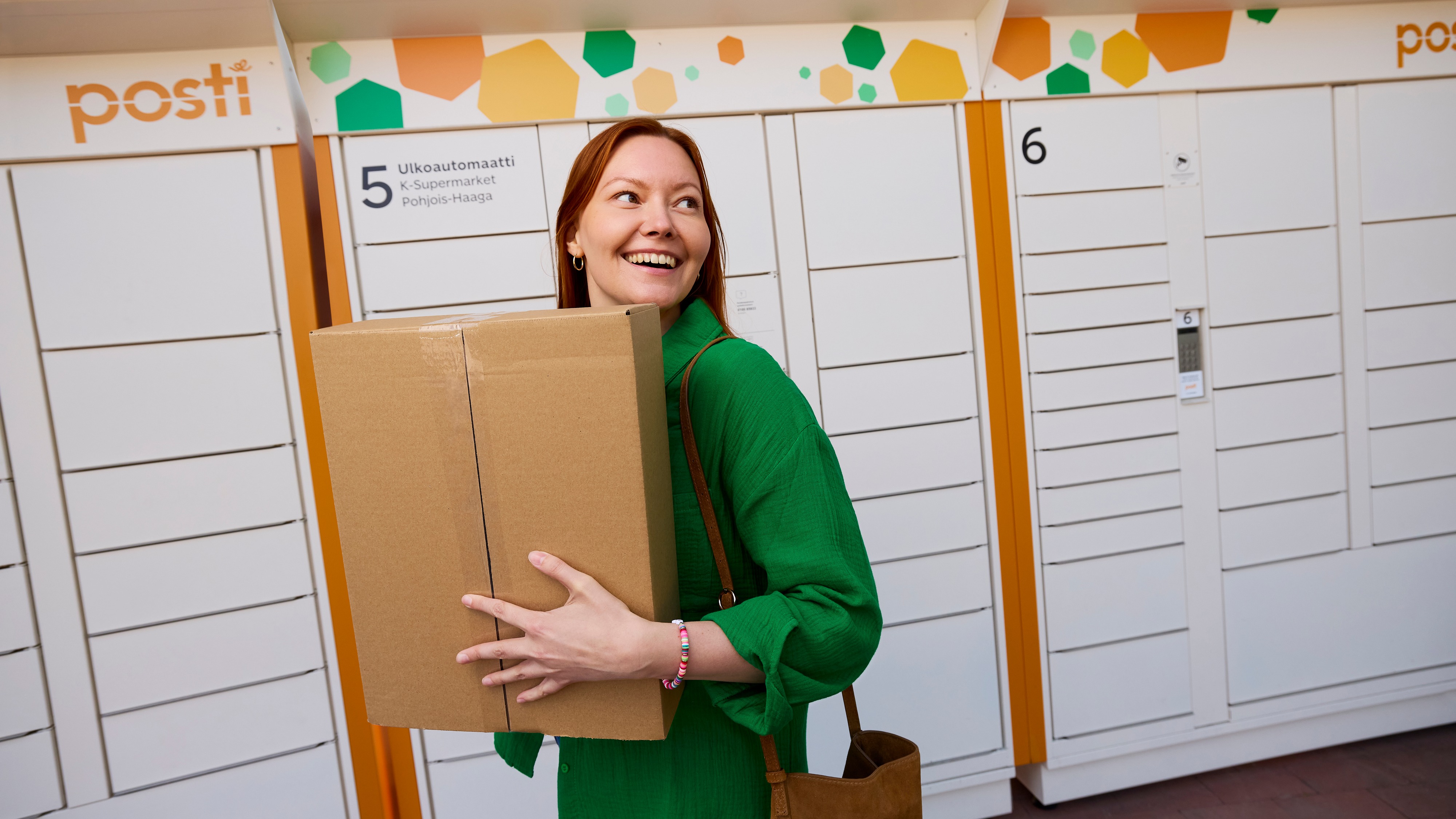 A woman carrying a parcel at Posti outdoor parcel locker