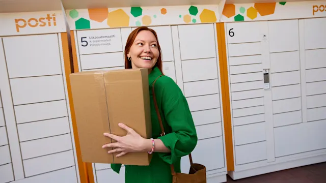 En kvinna med en paket på Postis utomhusautomat.