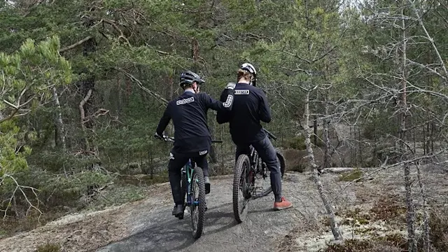 Kaksi pyöräilijää metsässä.