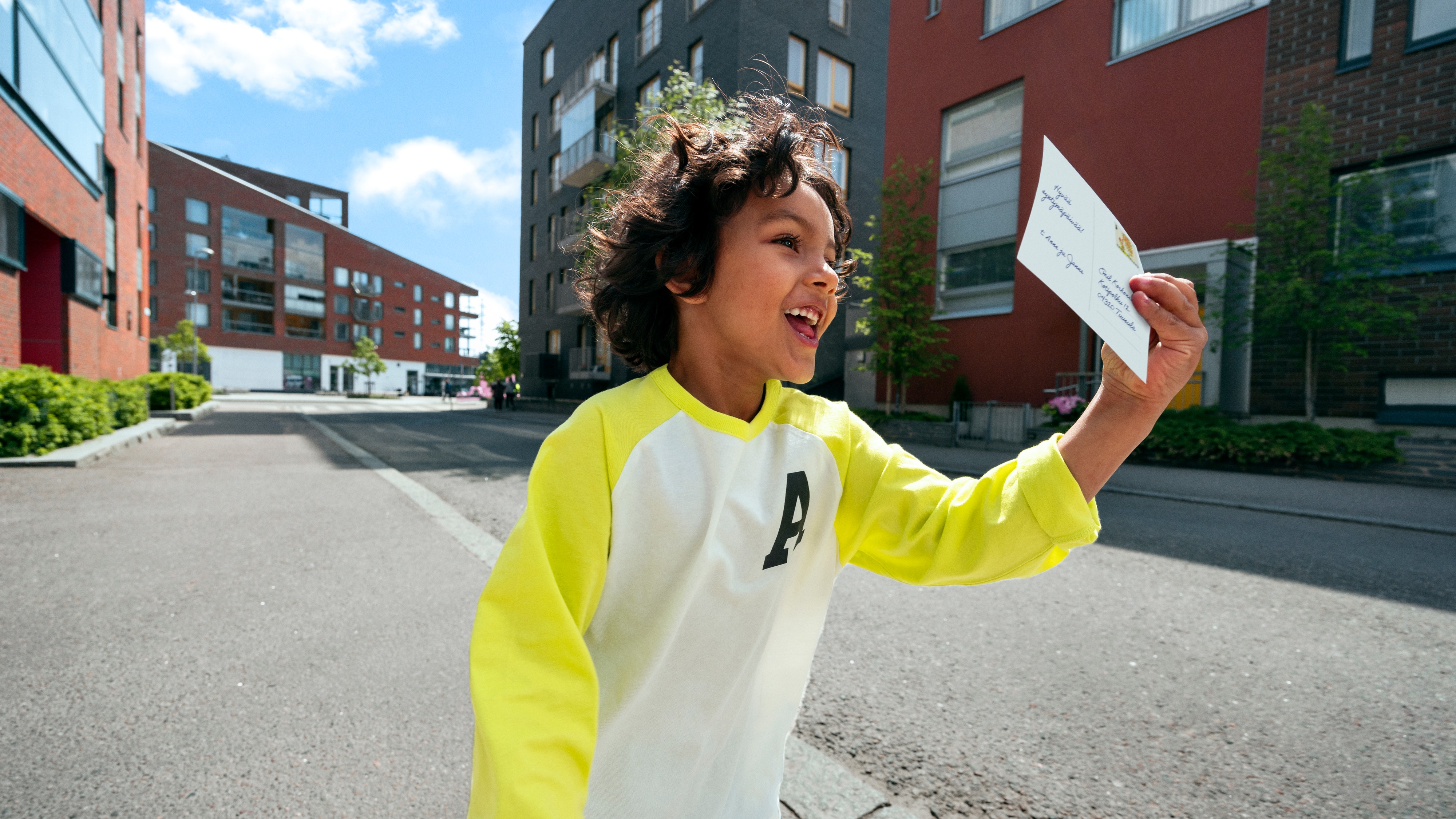 a smiling child holding a postcard.