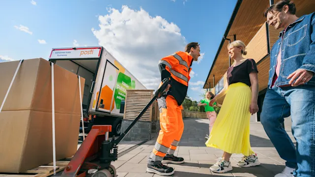 Postin logistiikkatyöntekijä tuo ison pakkauksen asiakkaille.