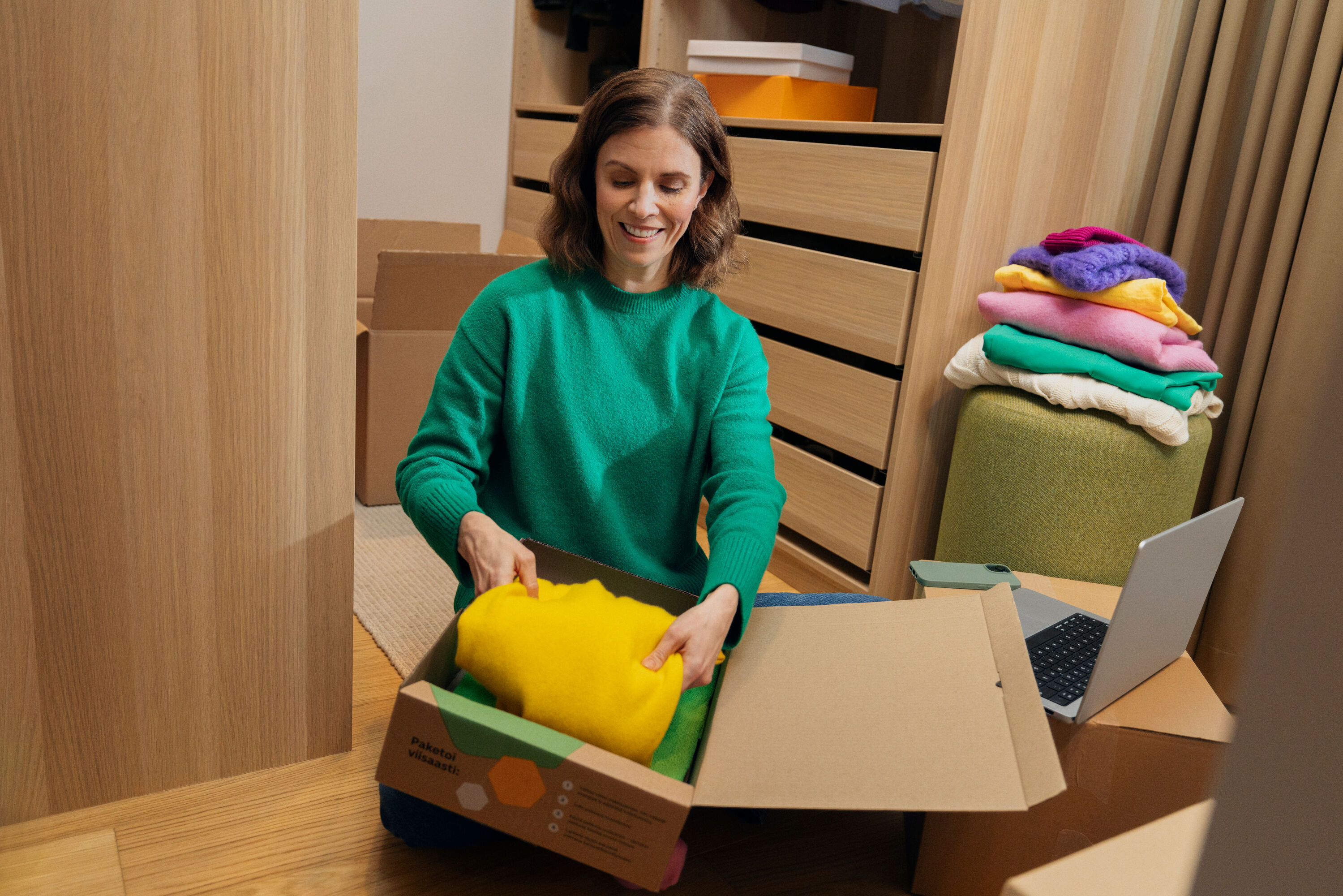 Nainen pakkaa vaatteita pakettiin