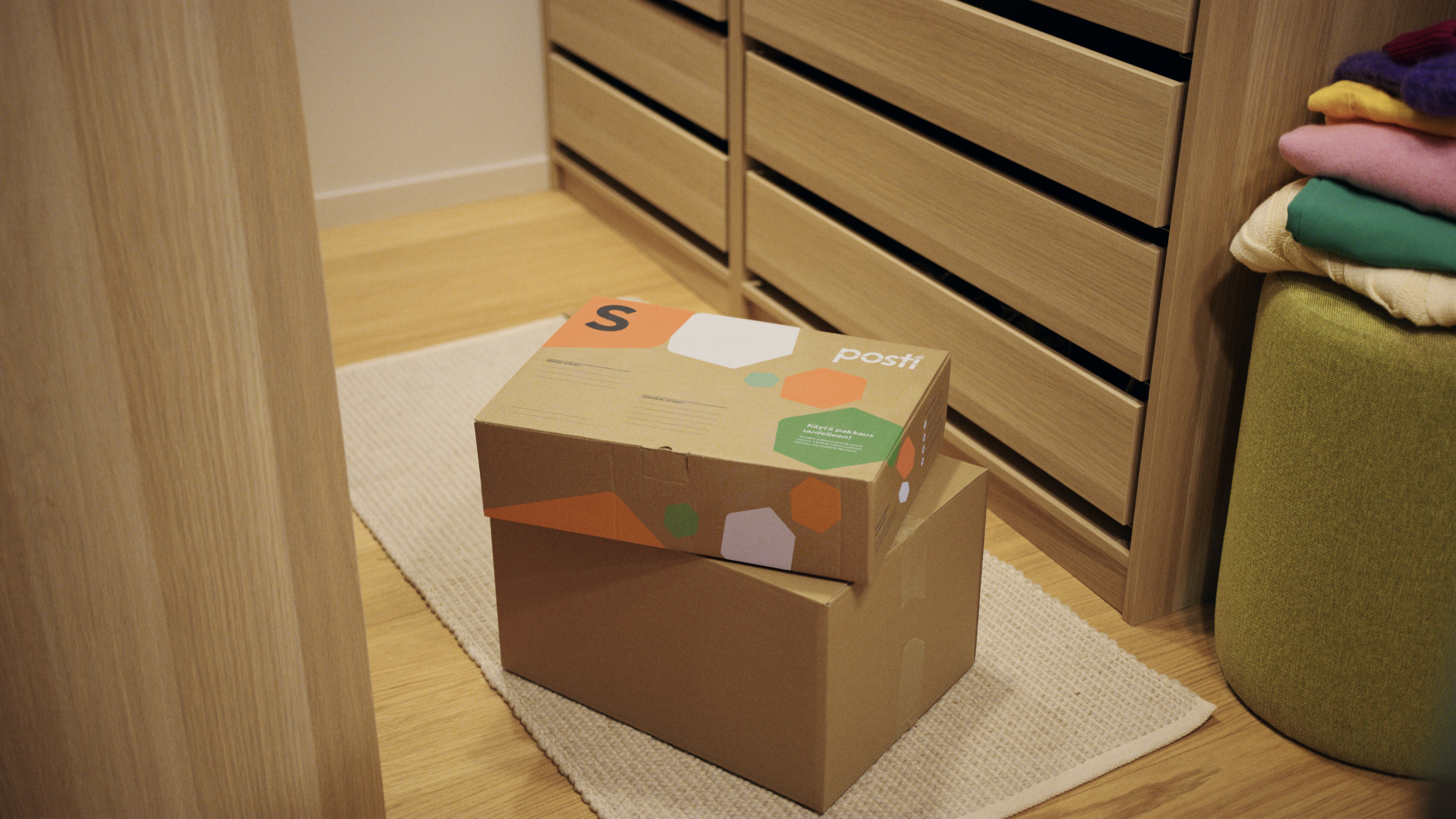 Two parcels on the floor of a walk-in closet, with a Posti size S parcel on top.