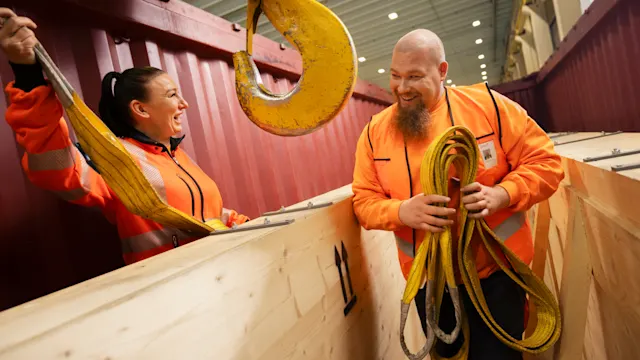 Postin logistiikkatyöntekijät valmistelevat isoa pakkausta kuljetukseen.