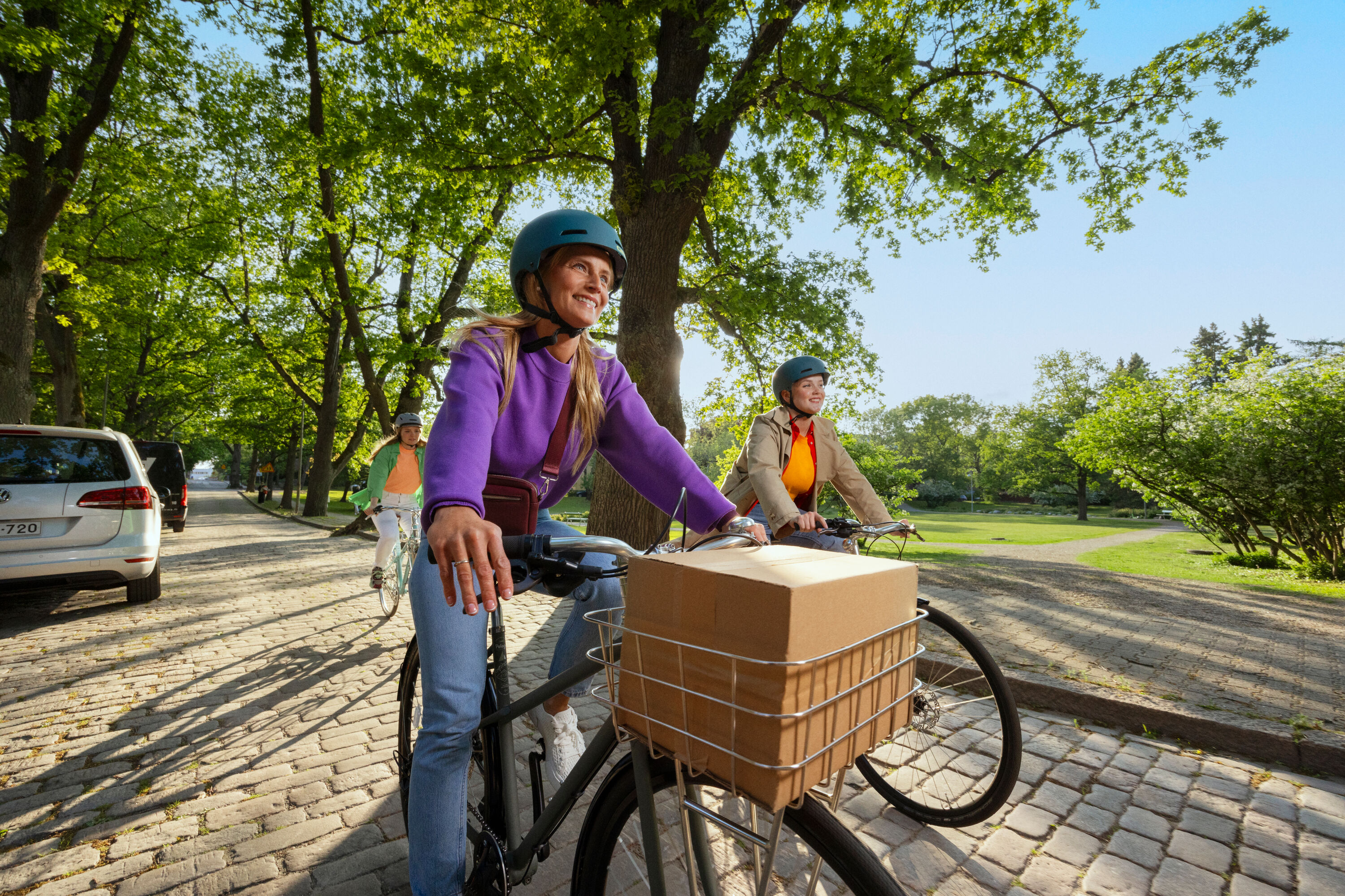 Two smiling people riding bicycles on a sunny day.