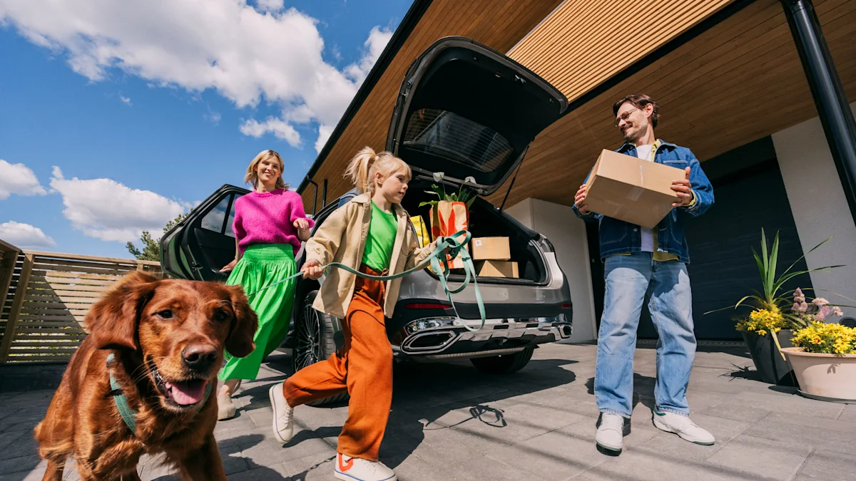 En familj lastar ur saker från bilens bagageutrymme framför huset. En hund är med.