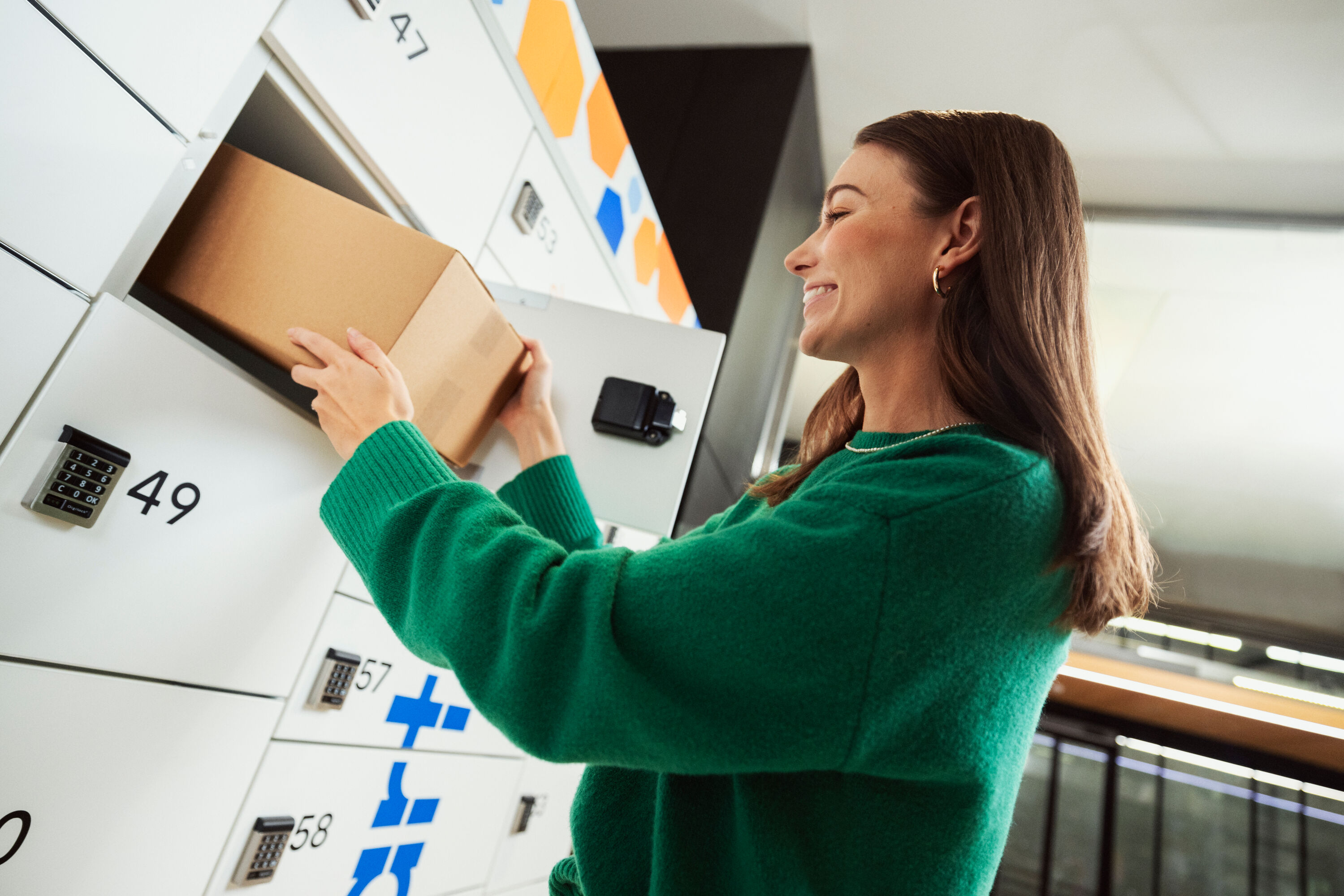 A woman in a green shirt using a parcel locker.