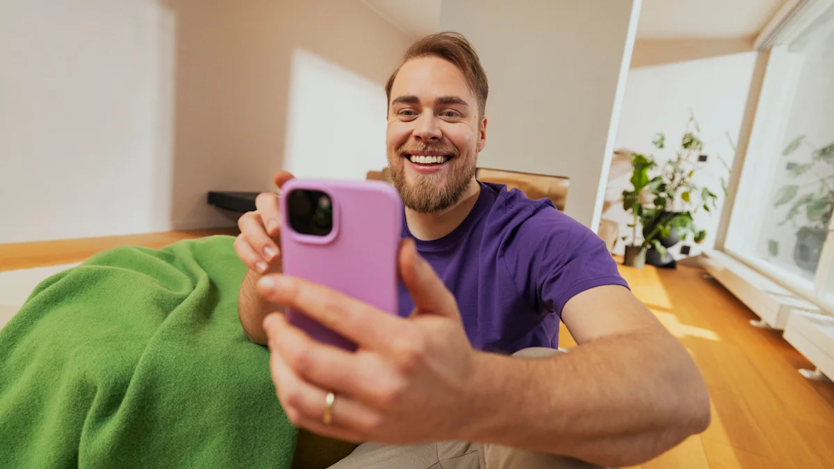A man smiles while using his phone with a pink case.