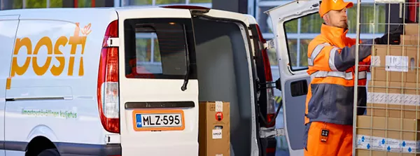 Posti's personnel is transfering packages to the transportation van.