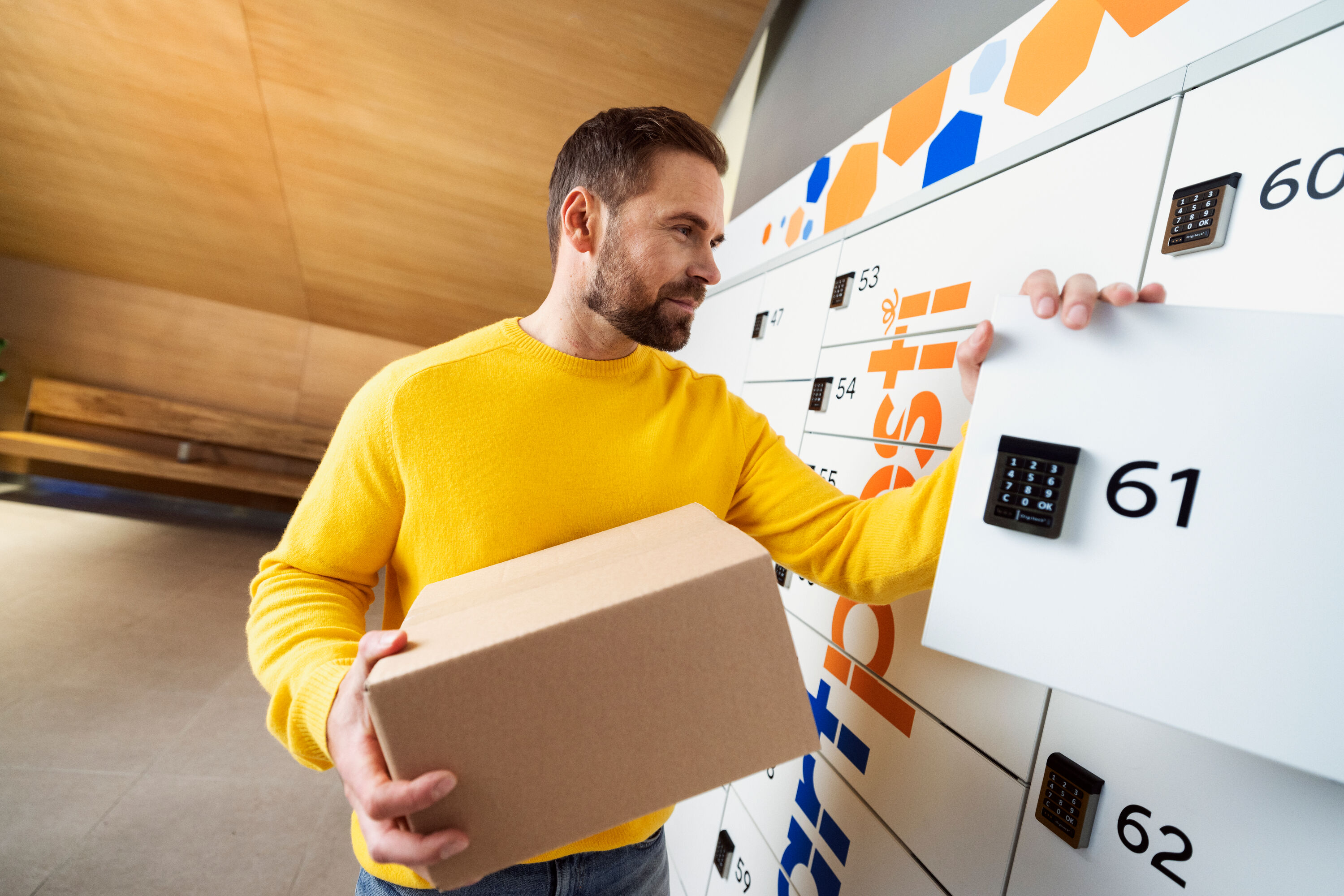 A man holding a package at a SmartPosti locker.