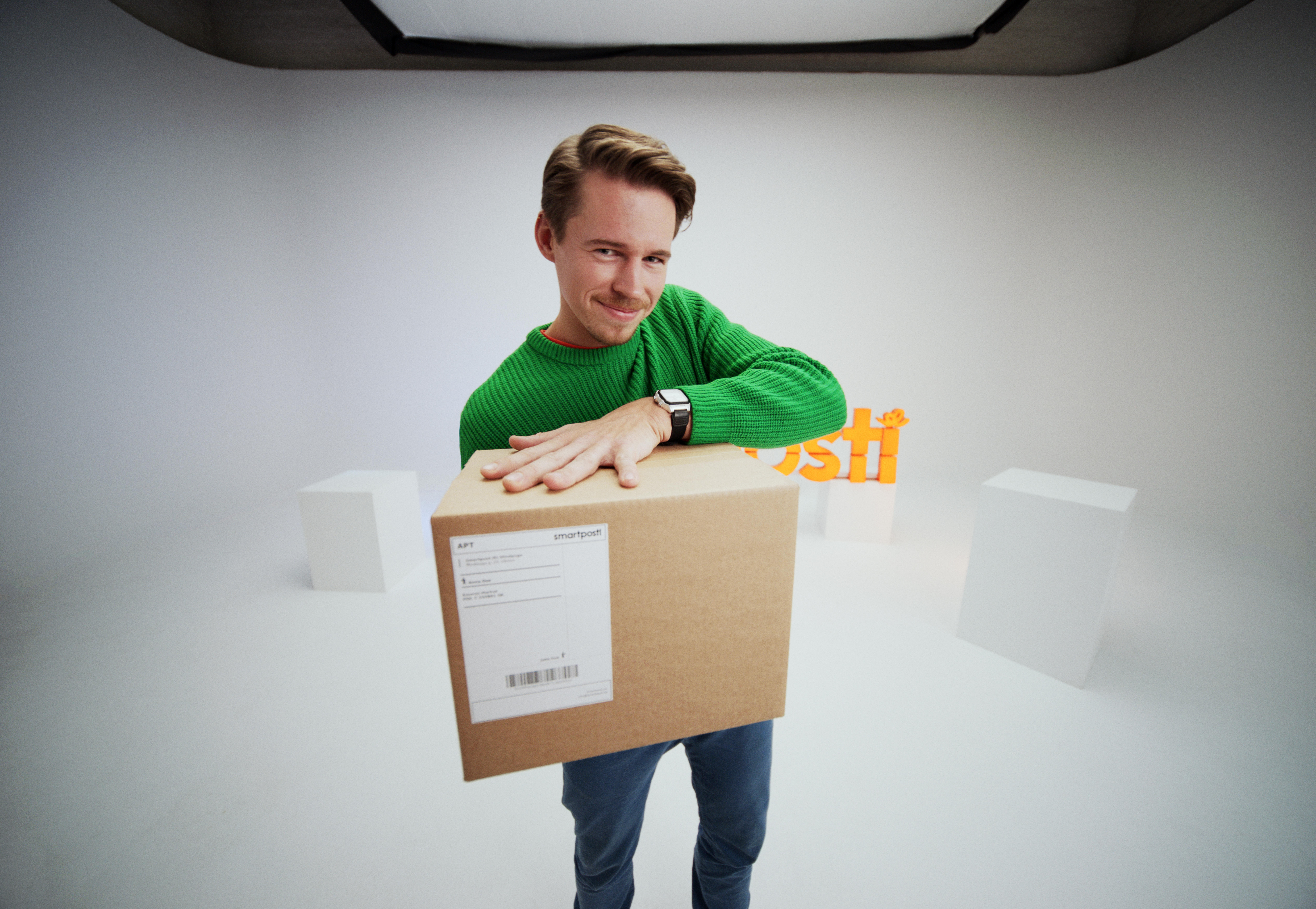 A woman in a pink shirt smiling and carrying a SmartPosti package.
