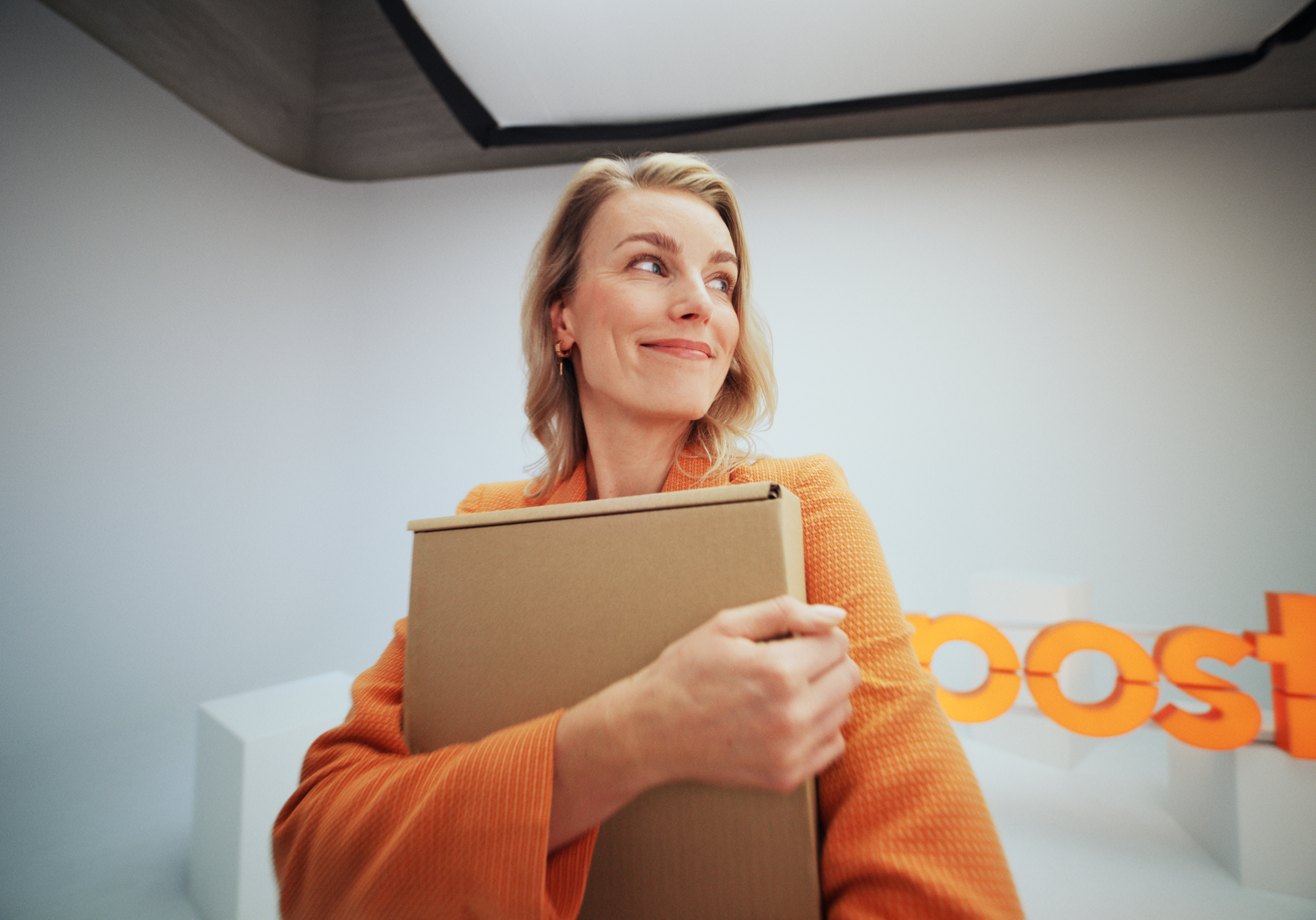 A woman in a pink shirt smiling and carrying a SmartPosti package.