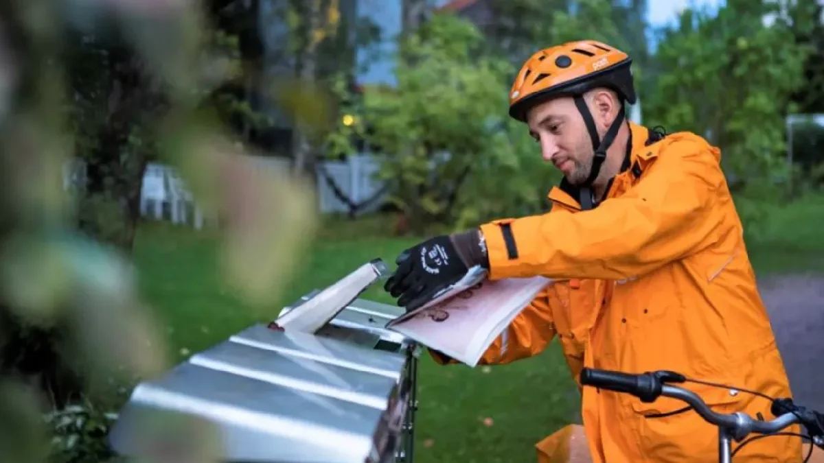 Mail delivery person delivering mail at a mailbox.