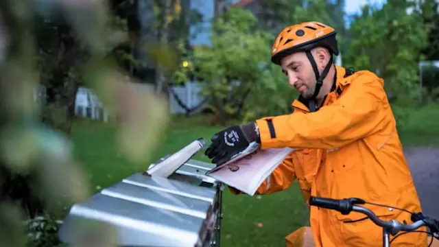 Postinjakaja jakaa postia postilaatikolla.