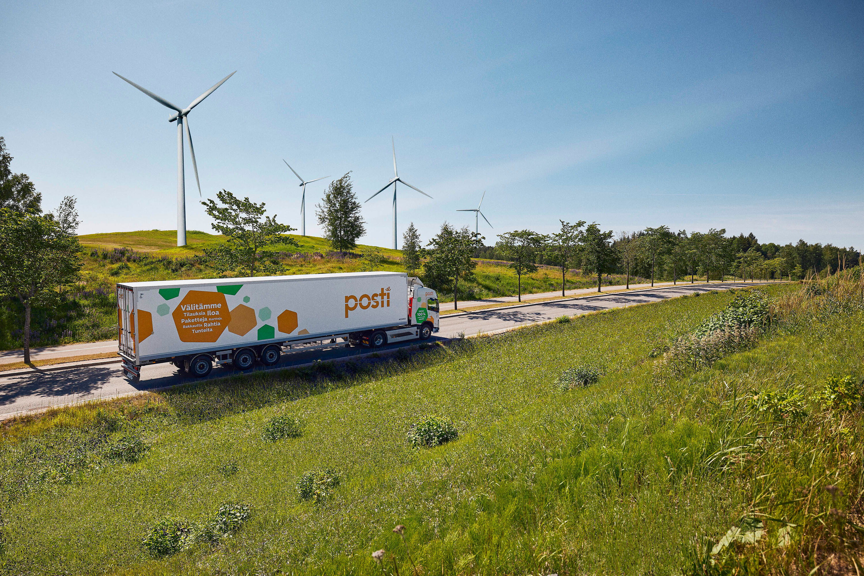 Posti truck on a road in summer with windmills in the background