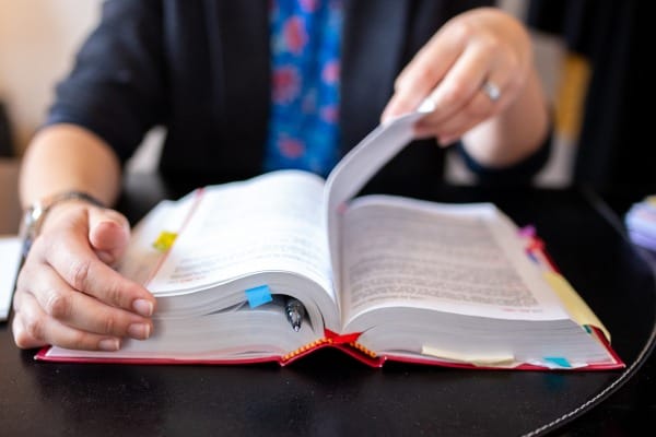 Closeup of law student flipping through a book with many bookmarked pages.