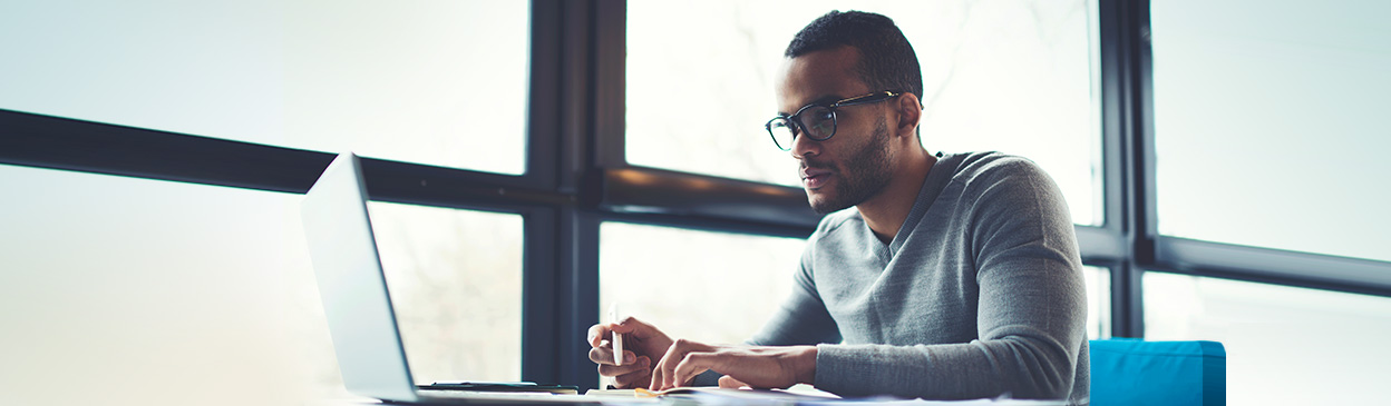 Man with glasses working on a laptop