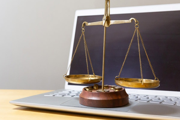 A small balance scale sitting on top of an open laptop keyboard.