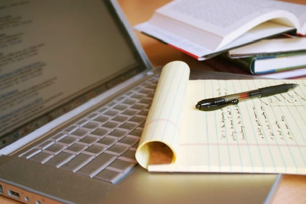 Closeup of laptop, notepad and open books