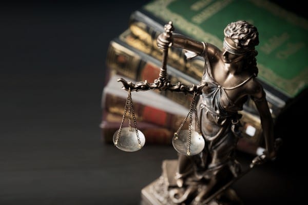 Lady justice statue with legal books stacked in the background