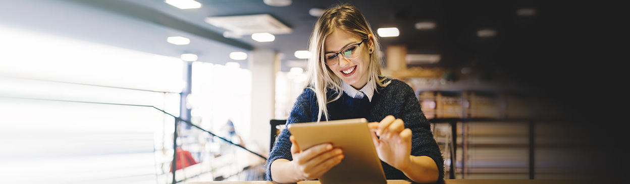 smiling woman on tablet in library