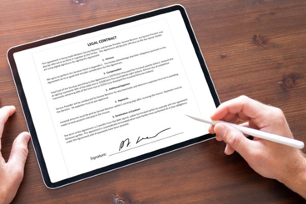 A person signs a contract on a mobile device.