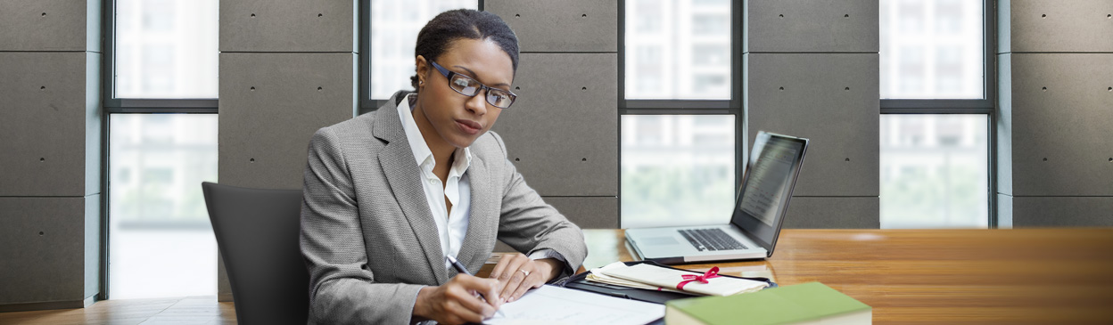 Female at table with computer, writing notes