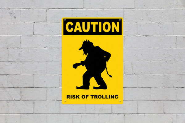 A yellow poster on a wall that says: Caution - Risk of Trolling.