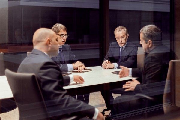 An executive board meets in a small meeting room.