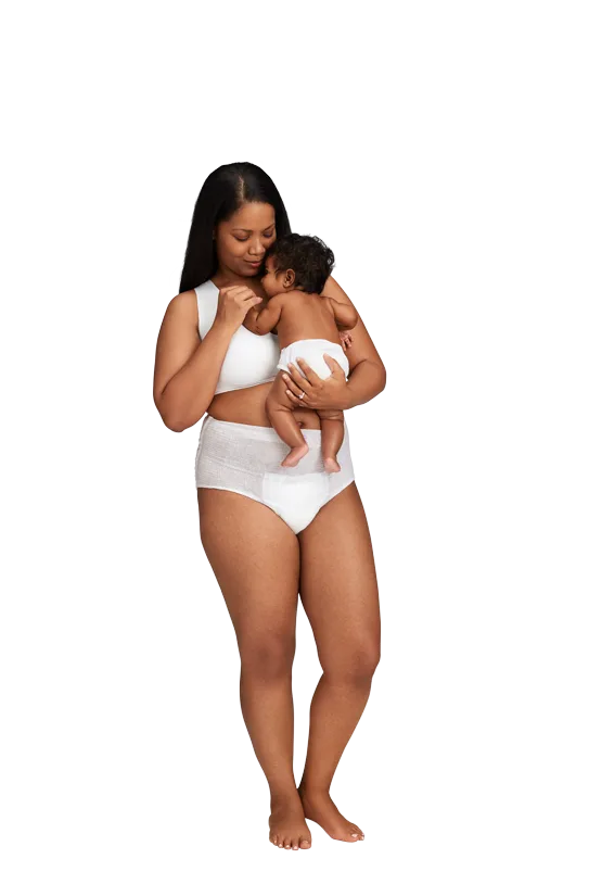 A woman in postpartum pants is holding a newborn baby in her arms