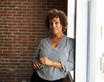 Smiling middle-aged woman standing near the window
