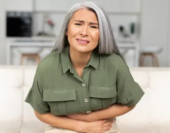 woman sitting on a sofa having bladder pain