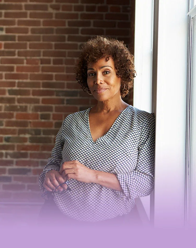 Smiling middle-aged woman standing near the window