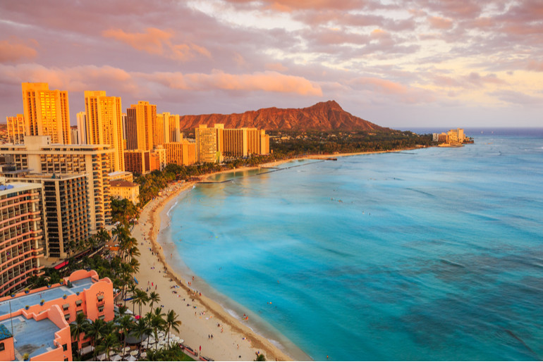 Aerial view of Honolulu’s coast with skyscrapers and a volcano