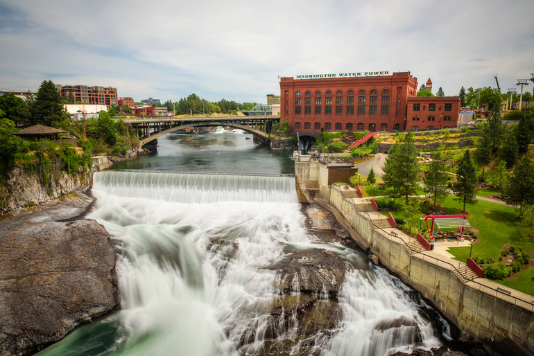 Spokane river rushing past Washington Water Power building and a green park