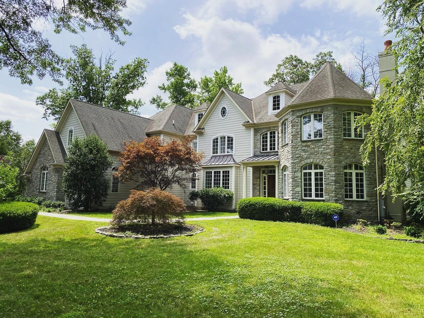 Tudor inspired home featuring Hardie plank lap siding in a custom color with stone accents and metal roof accent.