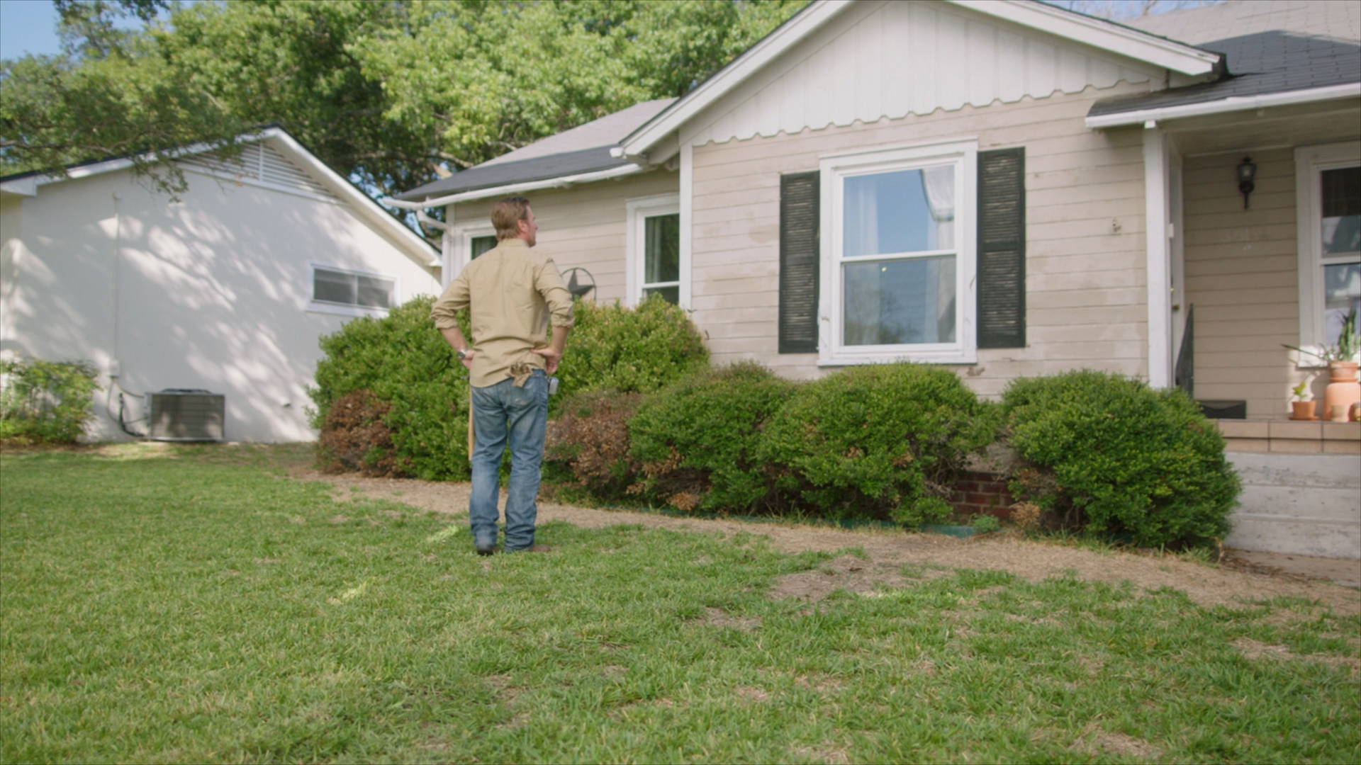 Chip Gaines examines the damaged siding on a home