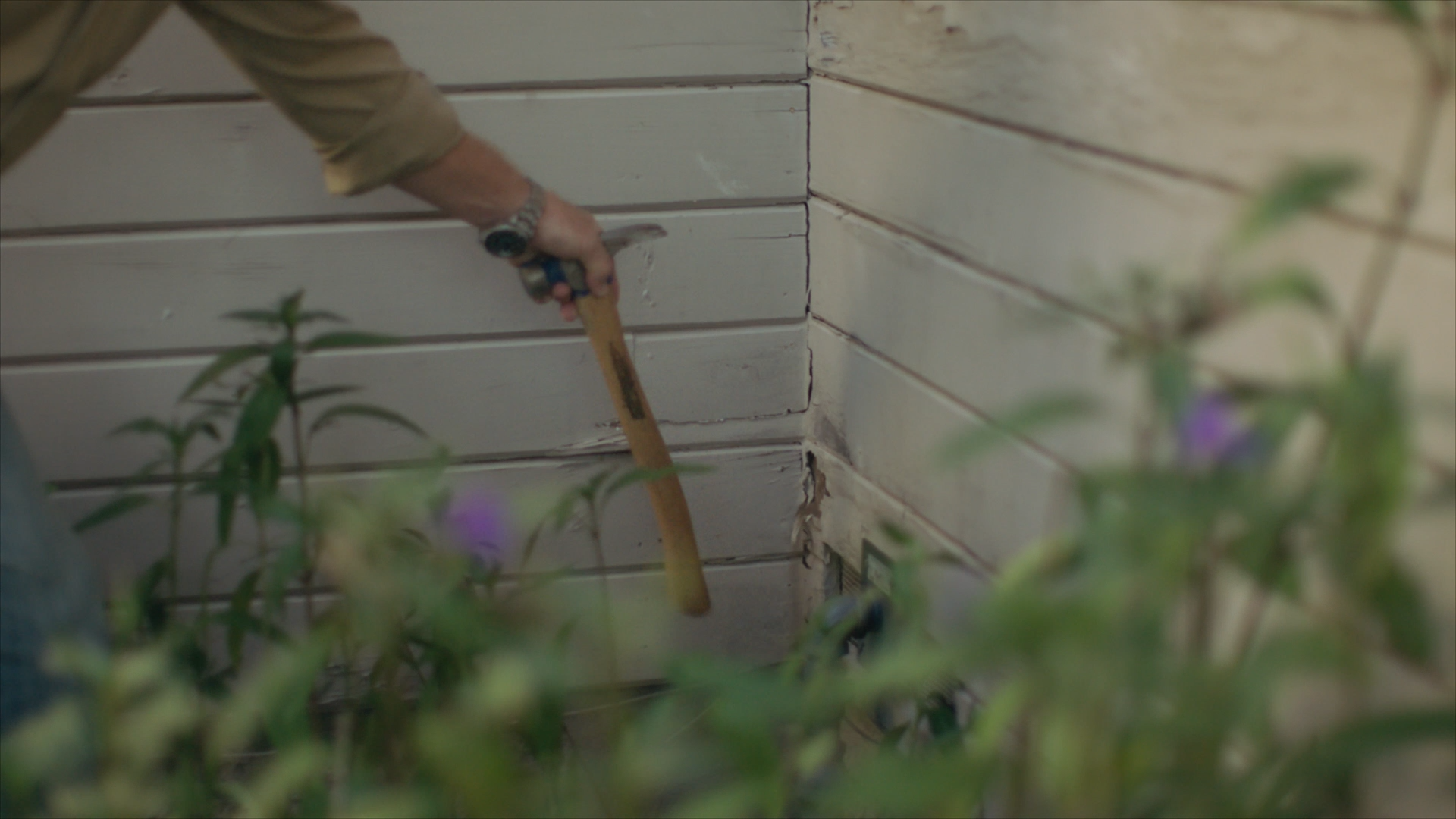 Chip Gaines pointing out cracked, water damaged siding 