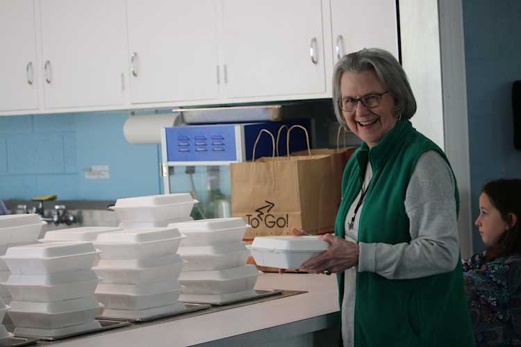 Church helper with food boxes smiling at camera